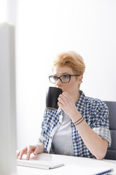 Junge Frau trinkt Kaffee am Schreibtisch - WESTF020510