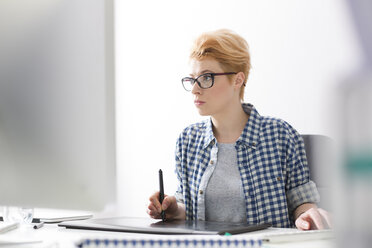 Junge Frau mit digitalem Tablet bei der Arbeit am Schreibtisch - WESTF020511