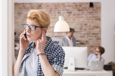 Seriöse junge Frau am Handy im Büro - WESTF020535