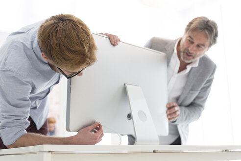 Zwei Männer in einem Büro, die einen Computerbildschirm anschließen - WESTF020542