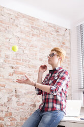 Junge Frau wirft Tennisball auf Schreibtisch - WESTF020595