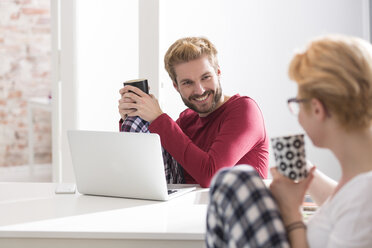 Young couple in pajamas with laptop on table - WESTF020621