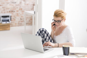 Young woman in pajamas using laptop - WESTF020624