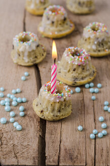 Mini-Vanille-Marmorkuchen mit brennenden Kerzen und hellblauen Perlen auf Holz - ODF001029