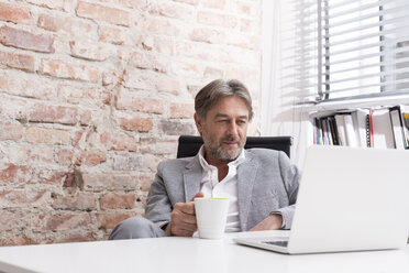 Businessman using laptop at desk - WESTF020630