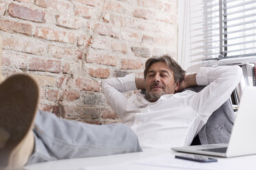 Relaxed businessman at desk leaning back - WESTF020633