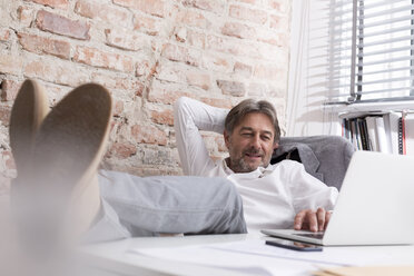 Relaxed businessman using laptop at desk - WESTF020634