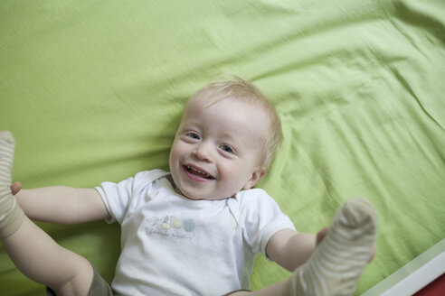 Porträt eines lächelnden kleinen Jungen auf dem Bett liegend - RB002241