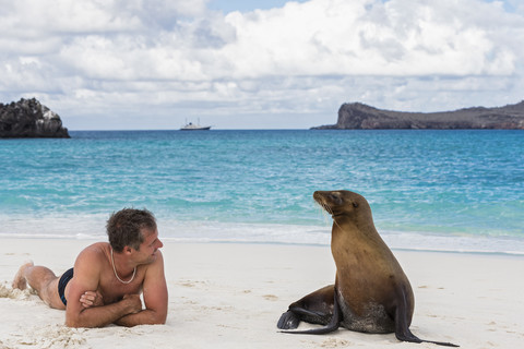 Ecuador, Galapagos-Inseln, Espanola, Tourist und Galapagos-Seelöwe am Strand, lizenzfreies Stockfoto