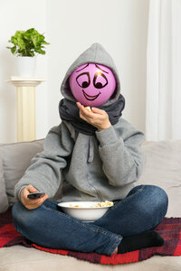 Ballonmensch mit Fernbedienung sitzt auf der Couch und isst Popcorn - MIDF000024