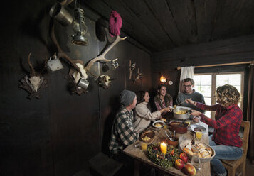 Gruppe junger Leute beim Essen in einer Berghütte - HHF005029