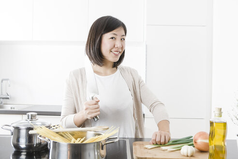 Porträt einer lächelnden jungen Frau beim Kochen - FLF000806