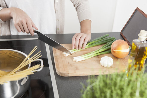Young woman cutting spring onions on wooden board - FLF000800