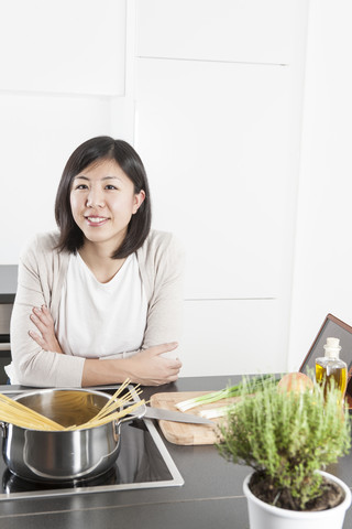 Porträt einer lächelnden jungen Frau, die Spaghetti kocht, lizenzfreies Stockfoto