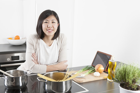 Porträt einer lächelnden jungen Frau, die Spaghetti kocht, lizenzfreies Stockfoto