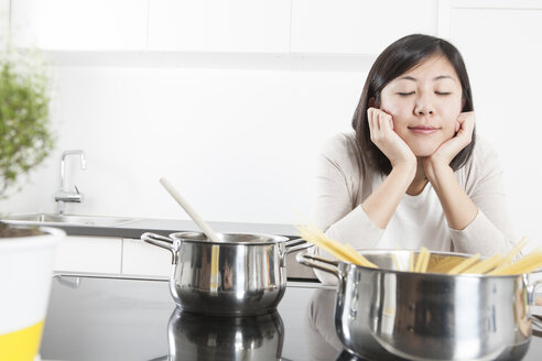 Portrait of smiling young woman relaxing while cooking - FLF000801