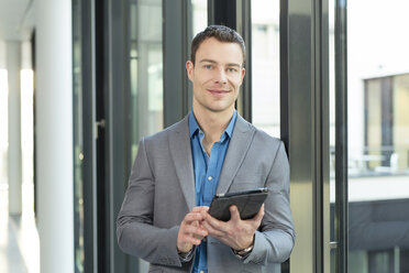 Portrait of smiling businessman with tablet computer in an office - SHKF000157