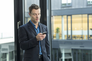 Businessman using smartphone in an office - SHKF000136