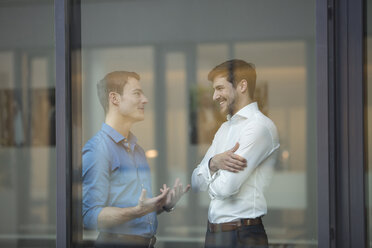 Two businessmen communicating behind window in an office - SHKF000162