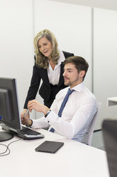 Geschäftsfrau und Geschäftsmann am Schreibtisch mit Blick auf den Computerbildschirm - SHKF000174