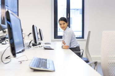 Porträt einer lächelnden Frau am Schreibtisch im Büro - SHKF000195