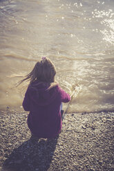 Little girl crouching at water's edge - SARF001237