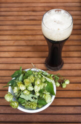Glass of black beer and bowl of hop on wood - JTF000618
