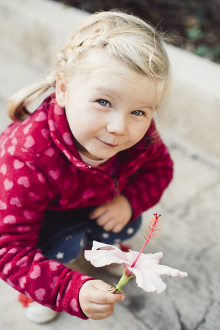 Portrait of little blond girl holding Hibiscus flower stock photo