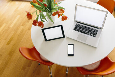 Three mobile devices on a white round table with red tulips and chairs - MFF001391