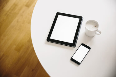 Tablet-PC und Smartphone mit einer Tasse Kaffee auf einem weißen runden Tisch - MFF001398