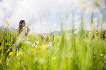 Young woman having picnic on alpine meadow - HHF005042