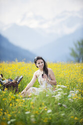 Junge Frau beim Picknick auf einer Bergwiese - HHF005048