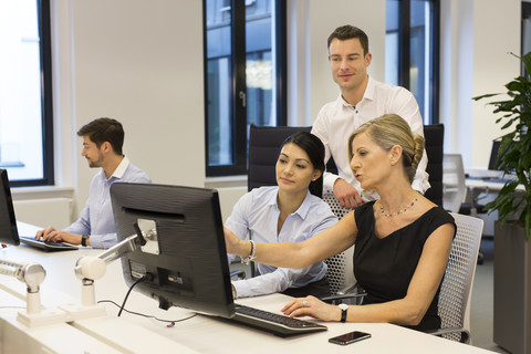 Geschäftsleute am Schreibtisch mit Blick auf den Computerbildschirm, lizenzfreies Stockfoto