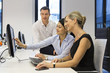 Businesspeople at desk looking at computer monitor - SHKF000205