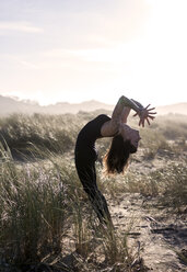 Spain, Asturias, Aviles, woman practicing yoga on the beach - MGOF000016