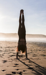 Spain, Asturias, Aviles, woman practicing yoga on the beach - MGOF000031