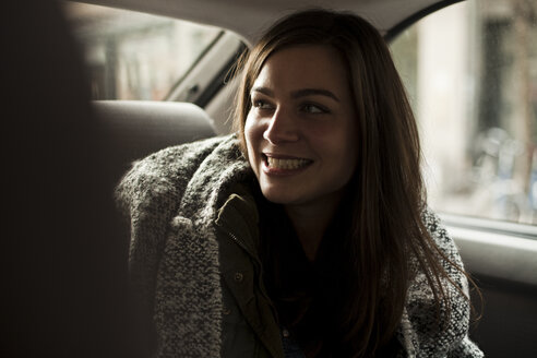 Portrait of smiling woman sitting on backseat of a car - FEXF000233
