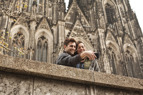 Deutschland, Köln, junges Paar beim Fotografieren vor dem Kölner Dom, lizenzfreies Stockfoto