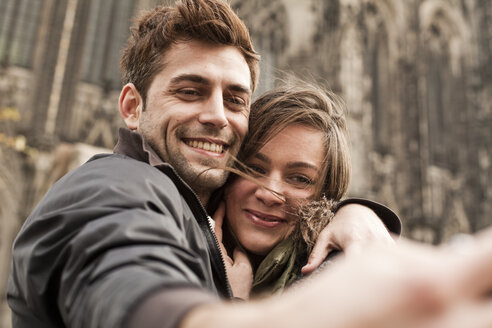 Germany, Cologne, young couple taking selfie in front of Cologne Cathedral - FEXF000239