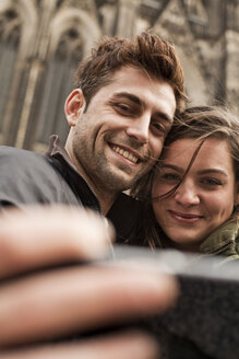 Germany, Cologne, young couple taking selfie in front of Cologne Cathedral - FEXF000240