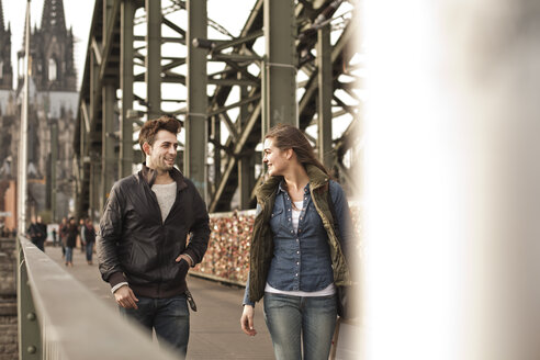 Germany, Cologne, young couple walking on Hohenzollern Bridge - FEXF000252