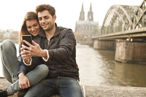 Germany, Cologne, young couple taking selfie in front of Cologne Cathredral - FEXF000276