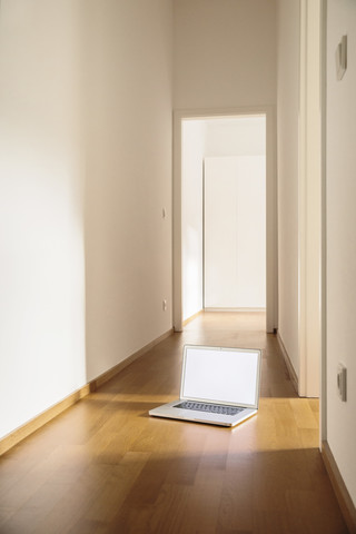 Laptop auf Holzfußboden im Flur stehend, lizenzfreies Stockfoto