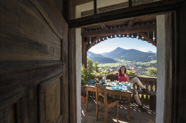 Austria, Salzburg State, Altenmarkt-Zauchense, woman enjoying breakfast on veranda of old farmhouse - HHF005054