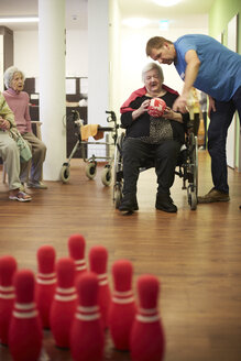 Altenpflegerin im Gespräch mit einer dementen Seniorin mit Schaumstoffball in einem Pflegeheim - DHL000504