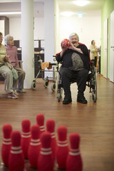 Altersdemente Seniorin beim Bowling mit Schaumstoffball in einem Pflegeheim - DHL000505