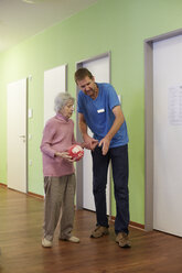 Altenpflegerin im Gespräch mit einer dementen Seniorin mit Schaumstoffball in einem Pflegeheim - DHL000508