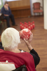 Altersdemente Seniorin beim Bowling mit Schaumstoffball in einem Pflegeheim - DHL000514