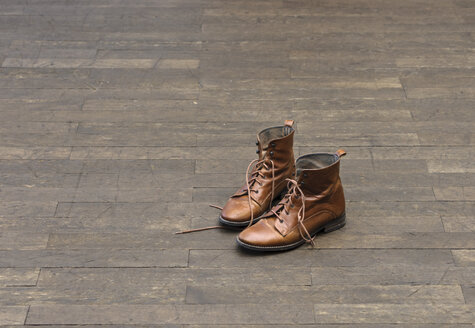 Pair of brown boots on wooden floor - LAF001278
