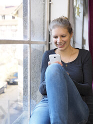 Lächelnde junge Frau, die ihr Smartphone benutzt - LAF001283